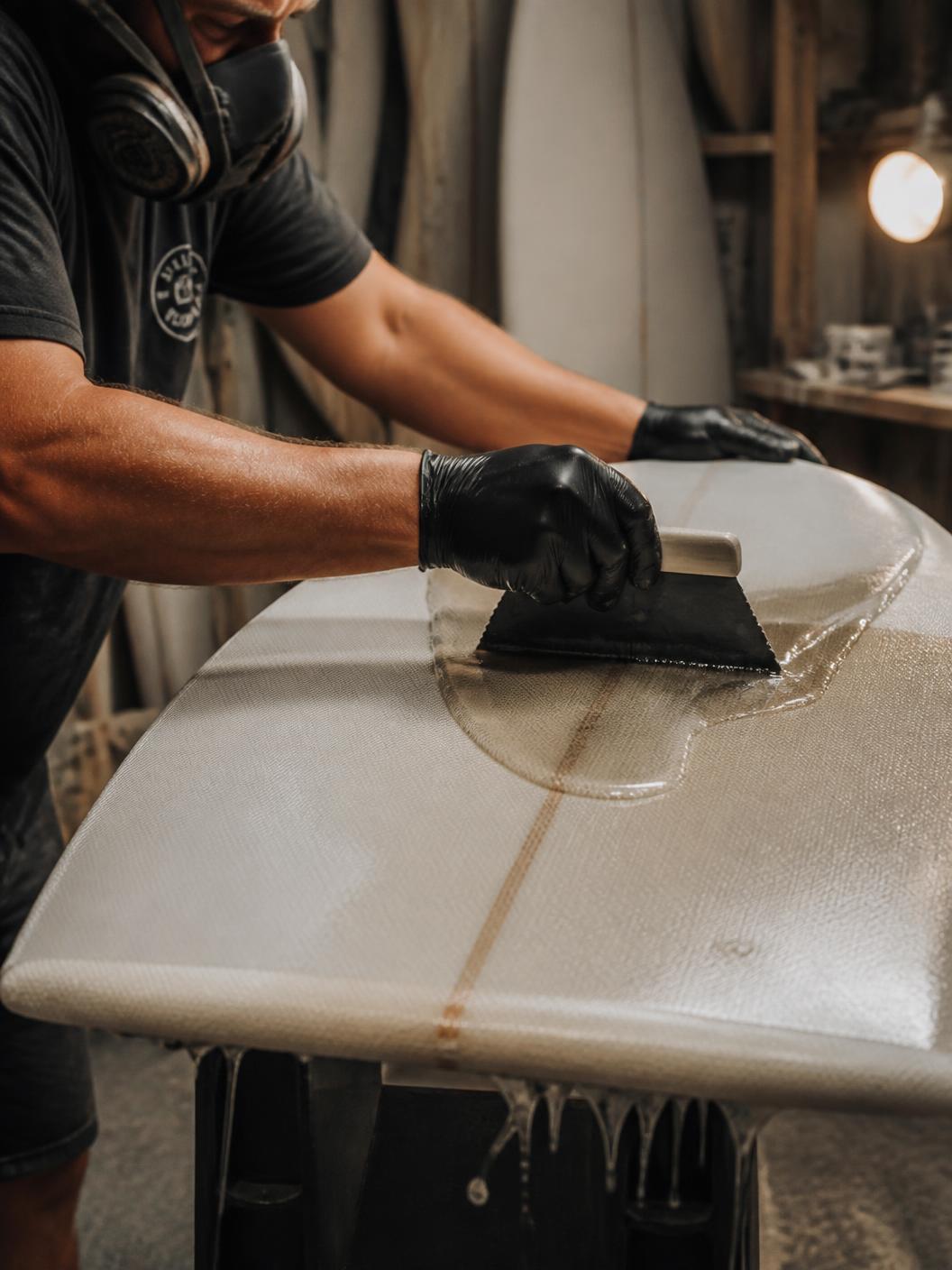 A Zeebrand shaper laminating a surfboard with resin and a squeegee